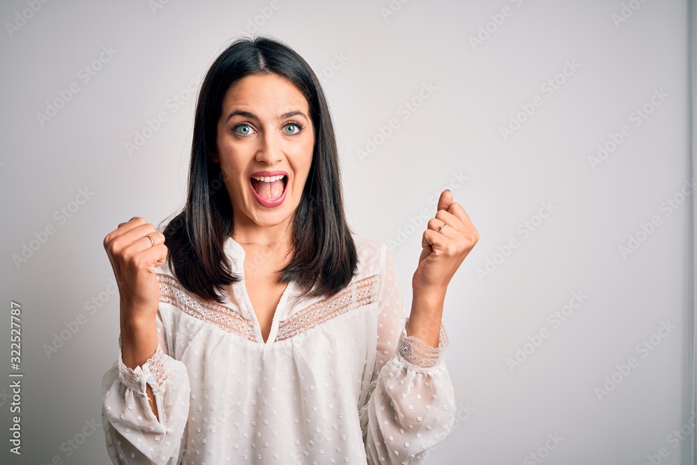 Young brunette woman with blue eyes wearing casual t-shirt over isolated white background celebrating surprised and amazed for success with arms raised and open eyes. Winner concept. Young brunette woman with blue eyes wearing casual t-shirt over isolated white background celebrating surprised and amazed for success with arms raised and open eyes. Winner concept.