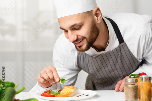 Chef Plating Roasted Salmon Steak And Decorating Dish In Kitchen