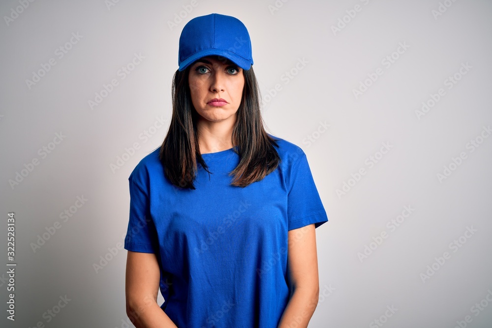 Young delivery woman with blue eyes wearing cap standing over blue background depressed and worry for distress, crying angry and afraid. Sad expression. Young delivery woman with blue eyes wearing cap standing over blue background depressed and worry for distress, crying angry and afraid. Sad expression.