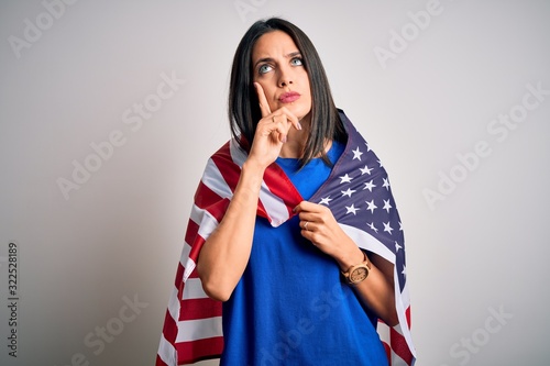 Young brunette patriotic woman with blue eyes wearing united states of america flag serious face thinking about question, very confused idea