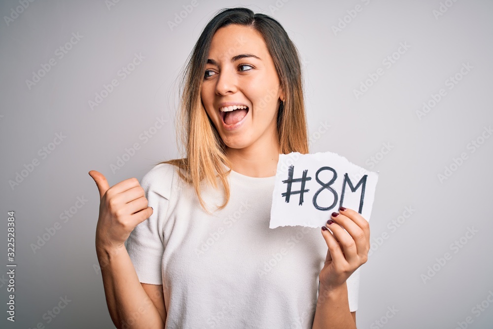 Beautiful woman with blue eyes celebrating 8th march womens day over white background pointing and showing with thumb up to the side with happy face smiling Beautiful woman with blue eyes celebrating 8th march womens day over white background pointing and showing with thumb up to the side with happy face smiling