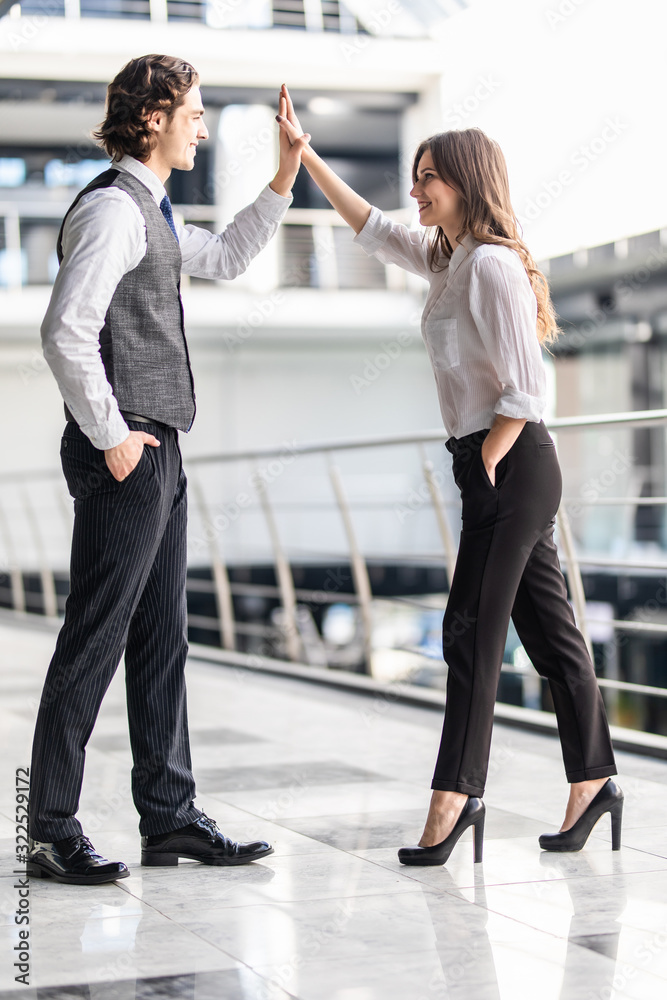 Fototapeta premium Beautiful business woman is giving high five and smiling to man during business meeting in office