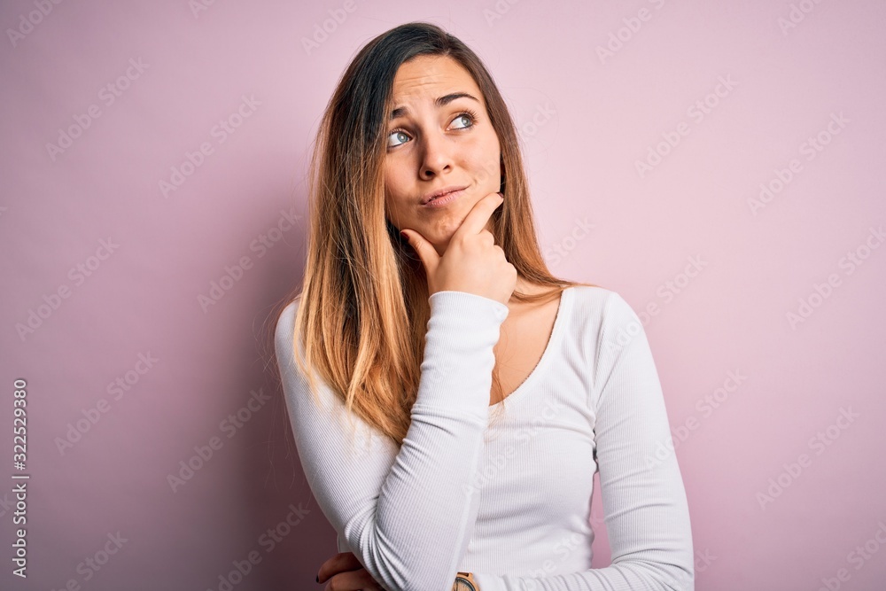Young beautiful blonde woman with blue eyes wearing white t-shirt over pink background Thinking worried about a question, concerned and nervous with hand on chin Young beautiful blonde woman with blue eyes wearing white t-shirt over pink background Thinking worried about a question, concerned and nervous with hand on chin