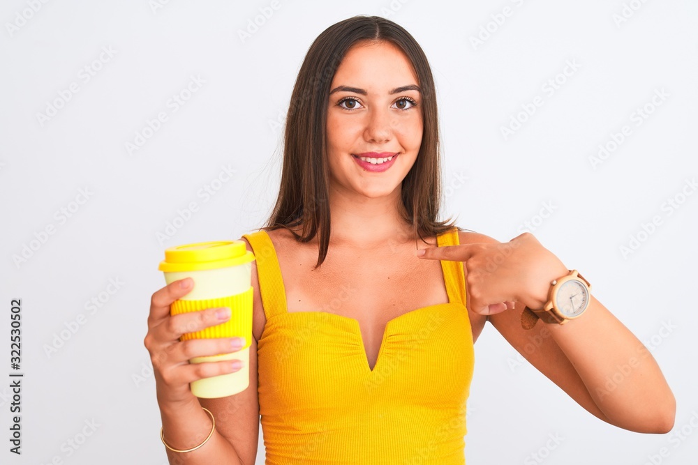 Young beautiful girl drinking paper glass of take away coffee over isolated white background with surprise face pointing finger to himself Young beautiful girl drinking paper glass of take away coffee over isolated white background with surprise face pointing finger to himself