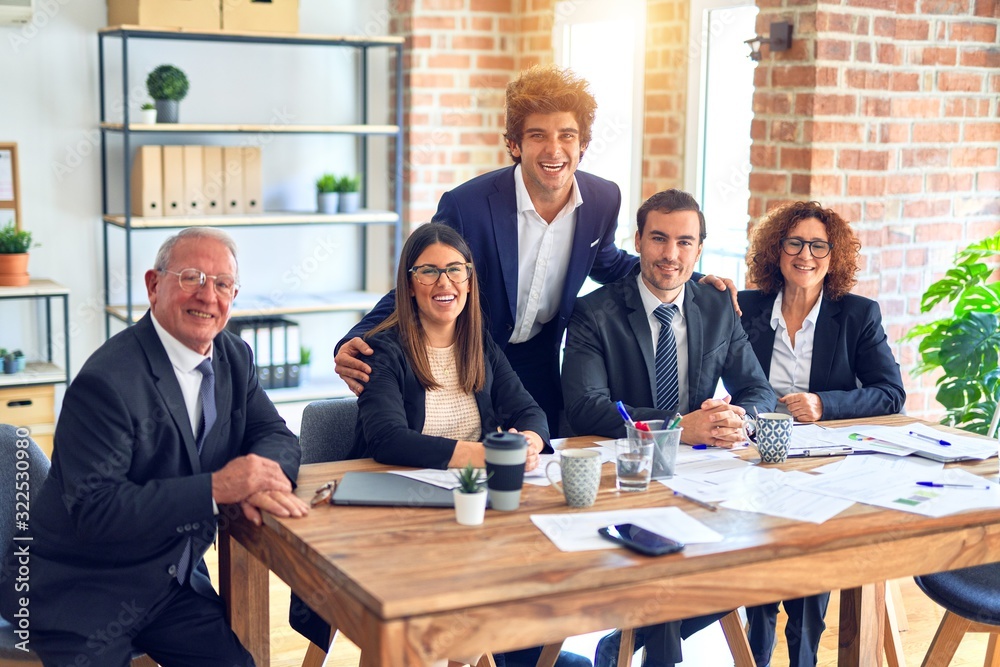 Obraz premium Group of business workers smiling happy and confident in a meeting. The boss standing and employees sitting with smile on face looking at the camera at the office