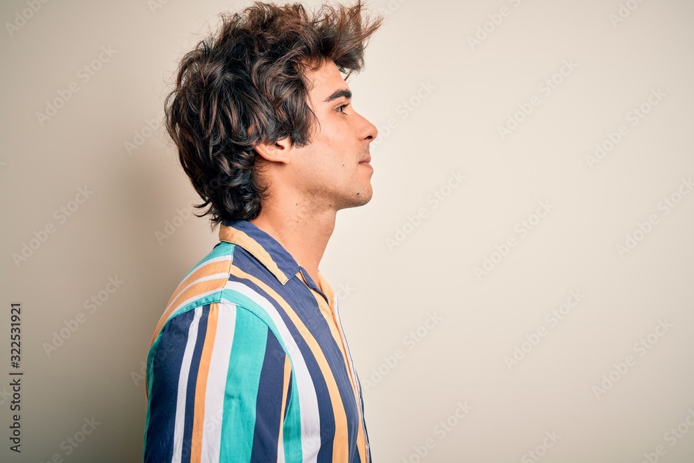 Young man on vacation wearing summer colorful shirt standing over isolated white background looking to side, relax profile pose with natural face with confident smile. Young man on vacation wearing summer colorful shirt standing over isolated white background looking to side, relax profile pose with natural face with confident smile.