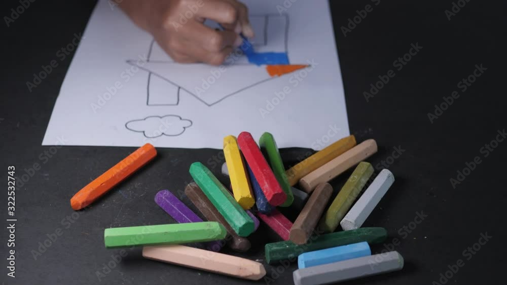 Close up of little girl is coloring in pastel crayons to stimulate creativity