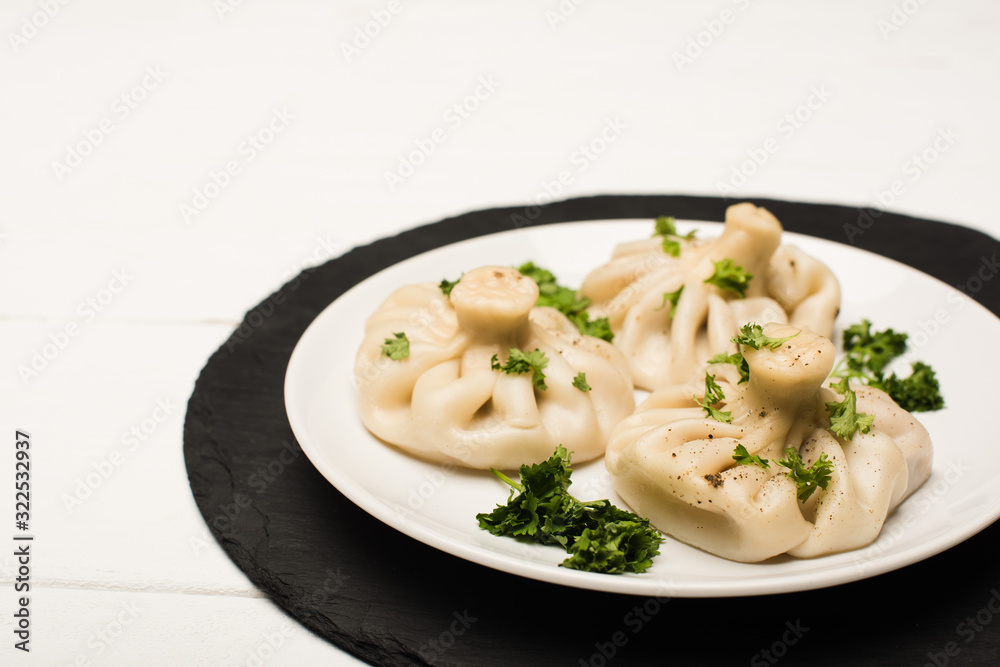 delicious Khinkali with cilantro on plate on white wooden table delicious Khinkali with cilantro on plate on white wooden table