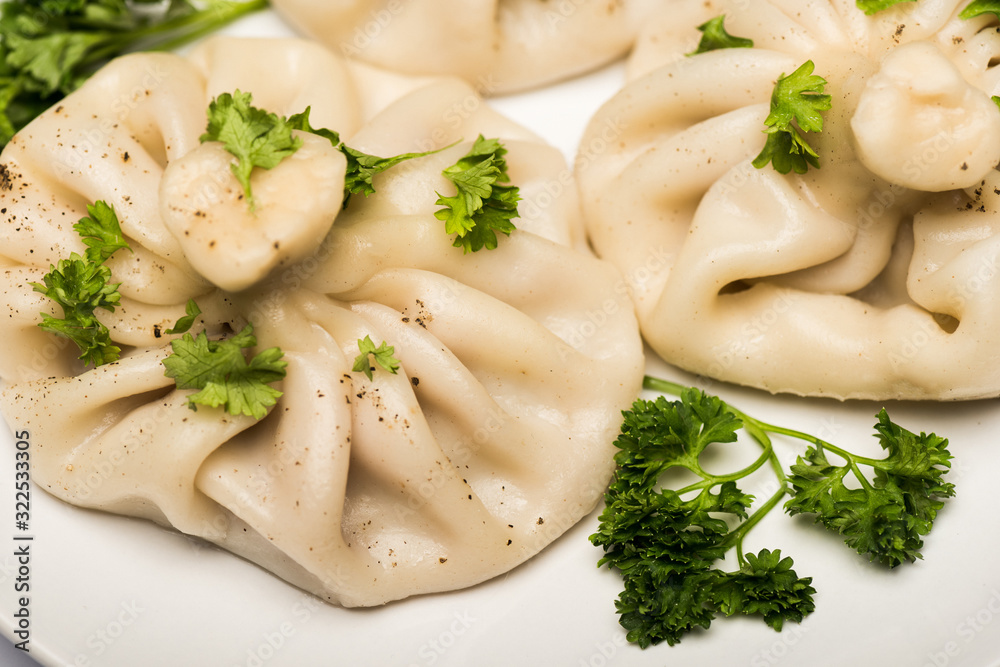 close up view of delicious Khinkali with cilantro and black pepper on white plate close up view of delicious Khinkali with cilantro and black pepper on white plate
