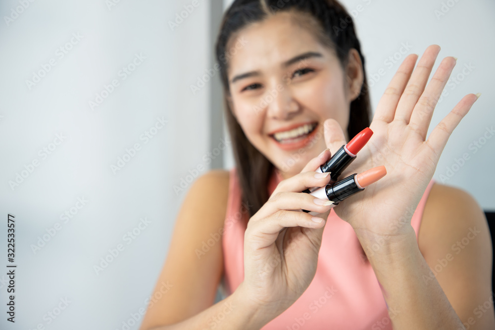Beautiful young woman show the color of lipstick before makeup. infront of a mirror at the living room. Woman using blush on concept. Beautiful young woman show the color of lipstick before makeup. infront of a mirror at the living room. Woman using blush on concept.