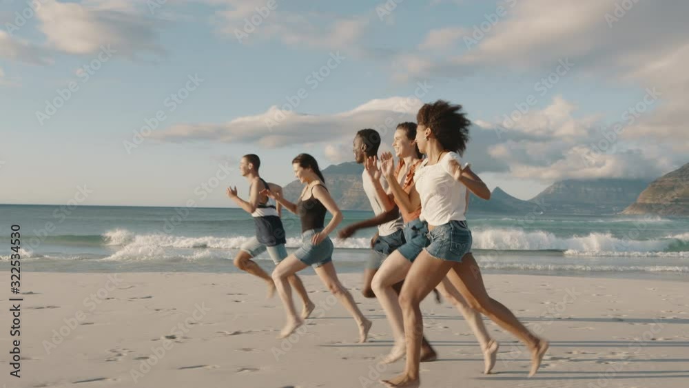 Young men and women running race on the beach. Group of friends playing games on the beach on a summer day.