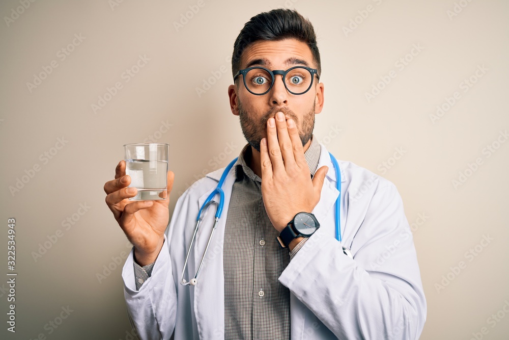 Young doctor man wearing stethoscope drinking a fresh glass of water over isolated background cover mouth with hand shocked with shame for mistake, expression of fear, scared in silence Young doctor man wearing stethoscope drinking a fresh glass of water over isolated background cover mouth with hand shocked with shame for mistake, expression of fear, scared in silence