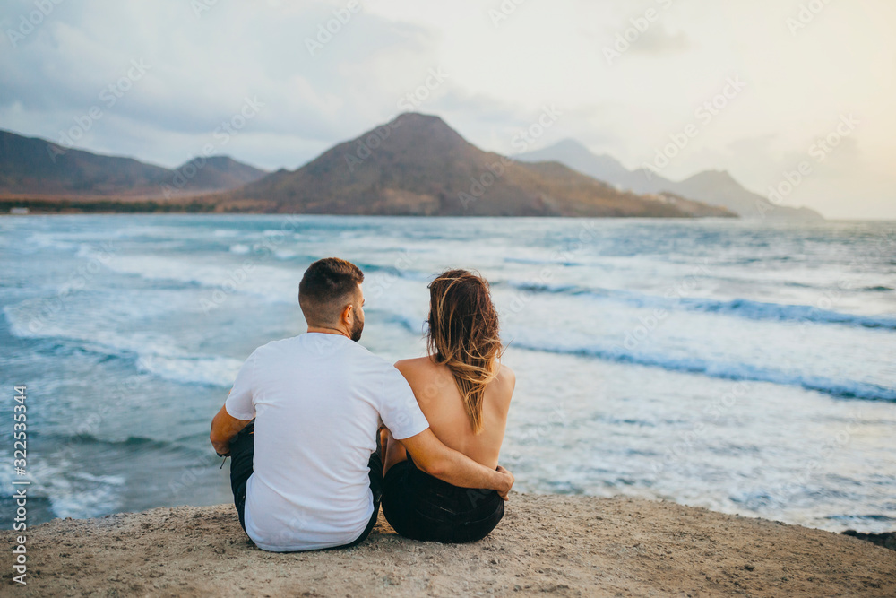 couple sitting in front of a beautiful landscape of the sea
