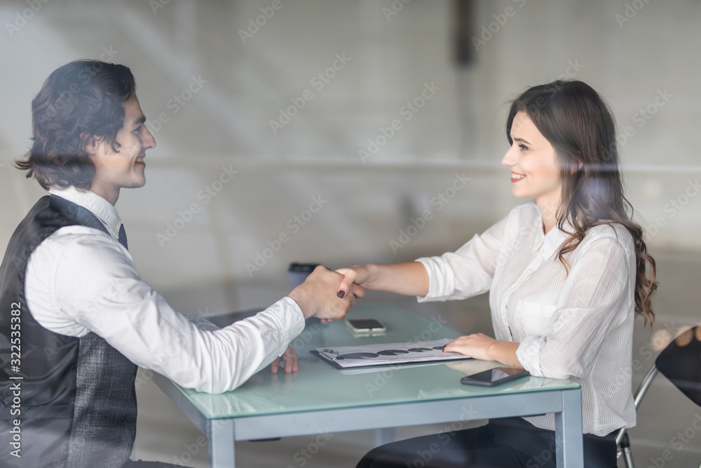 Friendly smiling businessman and businesswoman handshaking over the office desk after pleasant talk and effective negotiation, good relationships. Business concept photo Friendly smiling businessman and businesswoman handshaking over the office desk after pleasant talk and effective negotiation, good relationships. Business concept photo