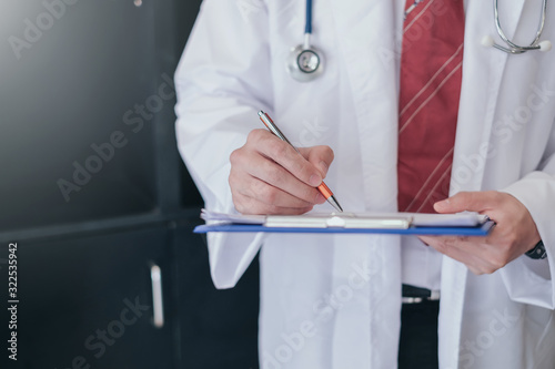 Male doctor writing on clipboard in the office.