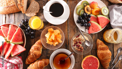 full breakfast with coffee cup, tea cup, croissant, bread and fruit