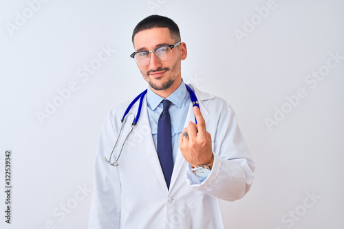 Young doctor man wearing stethoscope over isolated background Beckoning come here gesture with hand inviting welcoming happy and smiling