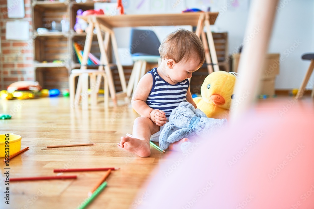 Fototapeta premium Adorable toddler playing around lots of toys at kindergarten