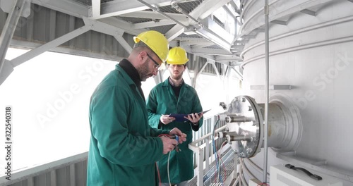 Due Ingegneri elettronici stanno controllando la temperatura all'interno della cisterna di raffreddamento photo