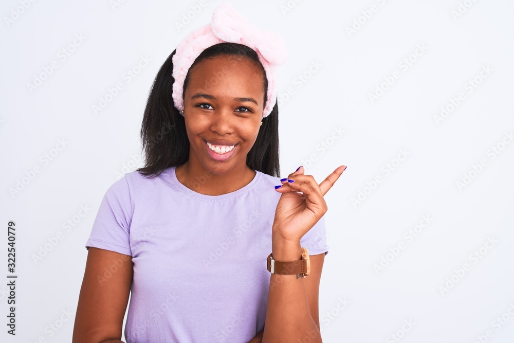 Beautiful young african american woman wearing a beauty diadem over isolated background very happy pointing with hand and finger to the side Beautiful young african american woman wearing a beauty diadem over isolated background very happy pointing with hand and finger to the side