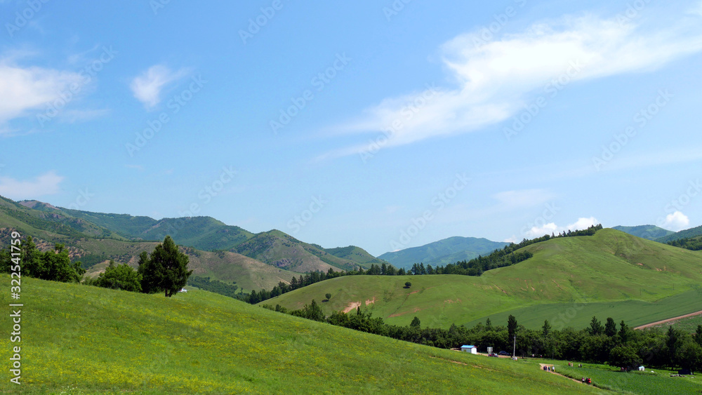 Green mountains in the summer sunlight against the blue sky