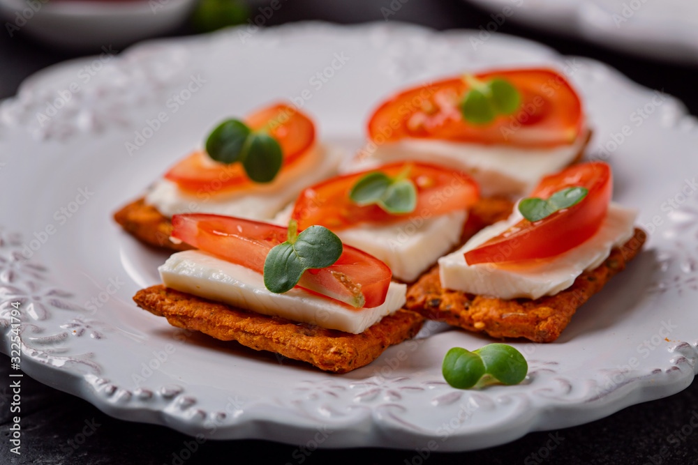 Canape  from  crackers with soft  cheese stracchino , tomato slice and green leaf.  