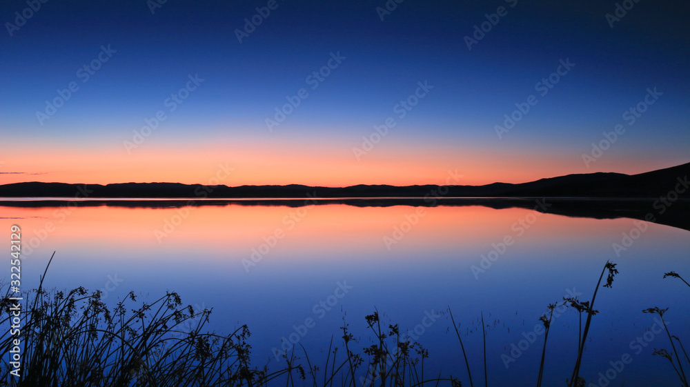Orange and blue sky reflected on the peaceful lake Orange and blue sky reflected on the peaceful lake