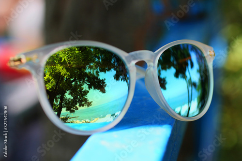 Reflective sunglasses with reflection of the sea and trees.Summer concept.