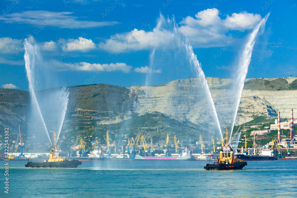 Floating tug boats are spraying jets of water, demonstrating their