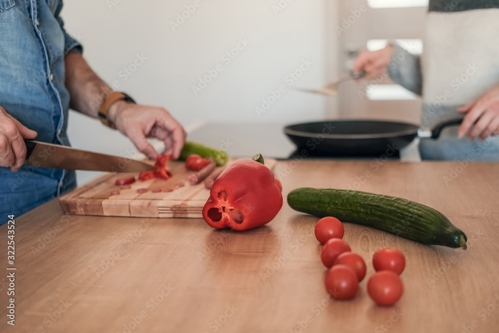 Handsome man cutting vegetables on wooden chopping board at kitchen counter. Handsome man cutting vegetables on wooden chopping board at kitchen counter.