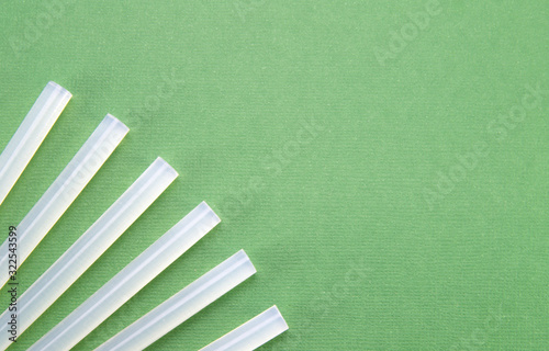 The transparent rods for the glue gun neatly fan out on a green background (table) in the corner. Sticks for thermal gun.