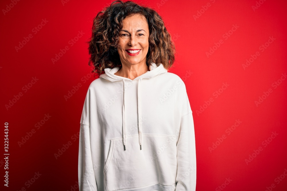 Fototapeta premium Middle age beautiful sporty woman wearing white sweatshirt over isolated red background with a happy and cool smile on face. Lucky person.