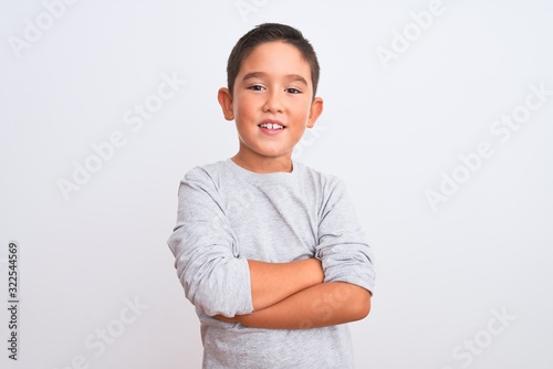 Beautiful kid boy wearing grey casual t-shirt standing over isolated white background happy face smiling with crossed arms looking at the camera. Positive person.