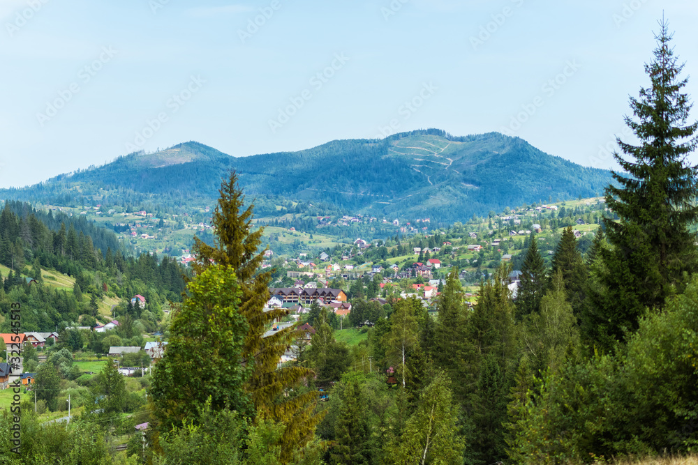 Amazing view of houses and pine-trees in Carpathian mountains in west part of Ukraine. Famous ukrainian mountains Carpathians. Scenic landscape. Tourist destination for summer and winter holidays