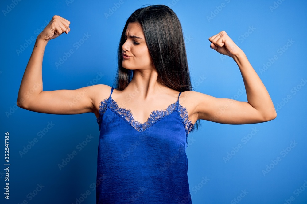 Fototapeta premium Young beautiful brunette woman wearing elegant and comfortable blue lingerie underwear showing arms muscles smiling proud. Fitness concept.