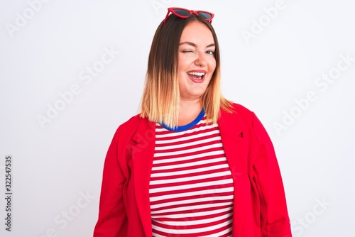 Young beautiful woman wearing striped t-shirt and jacket over isolated white background winking looking at the camera with sexy expression, cheerful and happy face.