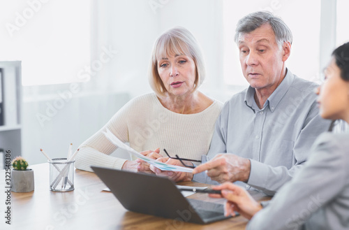 Focused mature couple talking to financial advisor at home