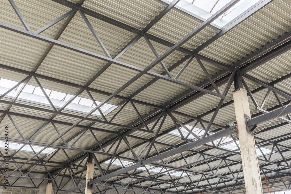 Aluminum roof with windows on a metal frame. Two reinforced concrete beams hold the structure. Construction of the hangar. Aluminum roof with windows on a metal frame. Two reinforced concrete beams hold the structure. Construction of the hangar.