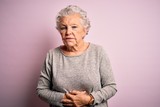 Senior beautiful woman wearing casual t-shirt standing over isolated pink background with hand on stomach because indigestion, painful illness feeling unwell. Ache concept.
