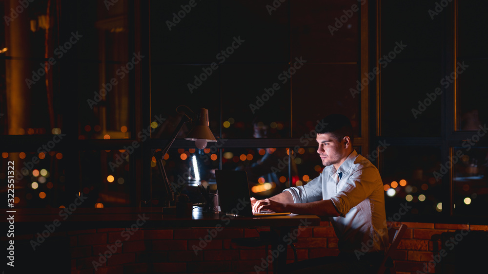 Man Working On Laptop Sitting In Office At Night, Panorama