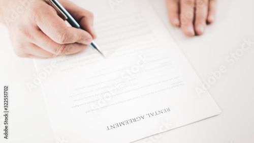Closeup of a businessman signing a rental agreement with a pen.