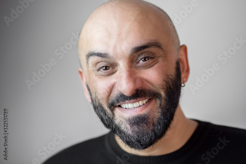 Bearded bald man with earring and beautiful white teeth smiling broadly