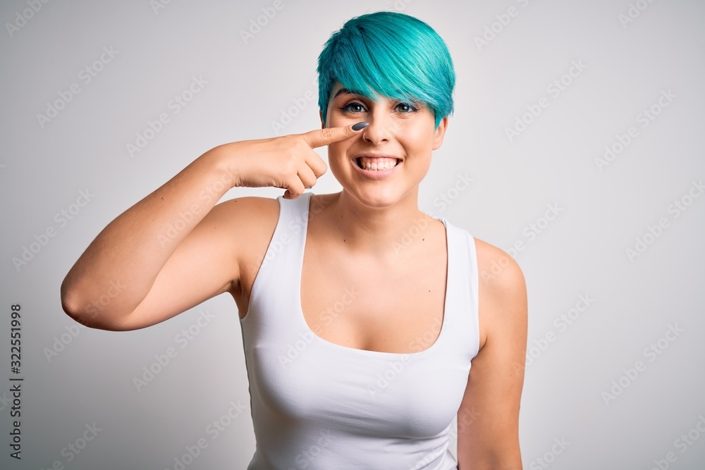 Young beautiful woman with blue fashion hair wearing casual t-shirt over white background Pointing with hand finger to face and nose, smiling cheerful. Beauty concept Young beautiful woman with blue fashion hair wearing casual t-shirt over white background Pointing with hand finger to face and nose, smiling cheerful. Beauty concept