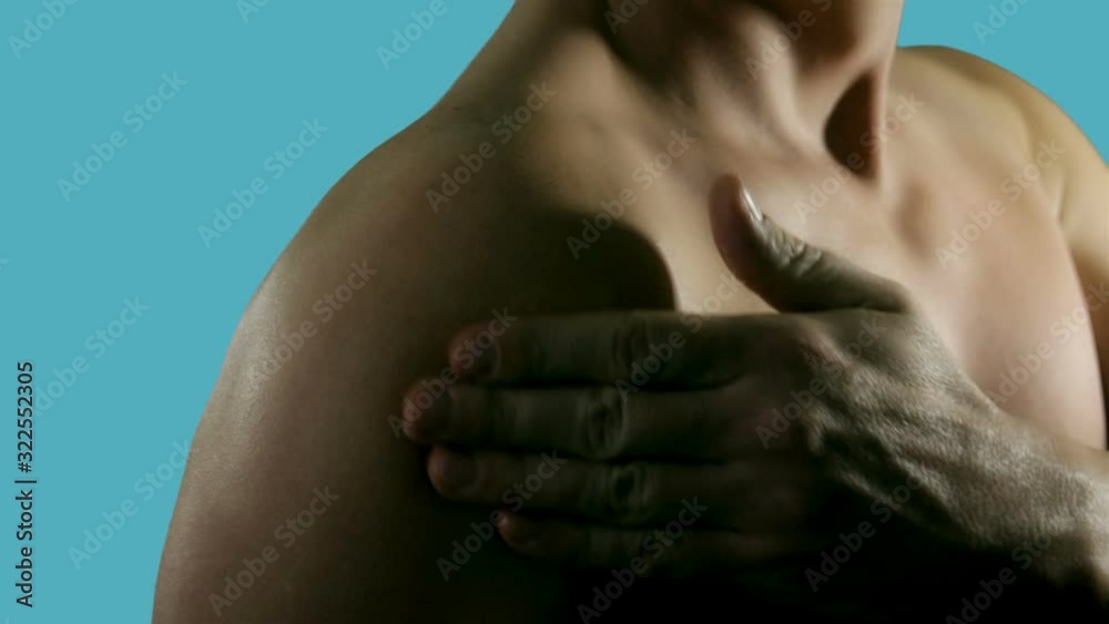 Young man standing over blue background and applying pain relief gel on his shoulder. Sport, bodybuilding, medicine and people concept Young man standing over blue background and applying pain relief gel on his shoulder. Sport, bodybuilding, medicine and people concept