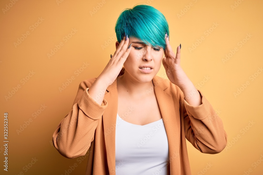 Young beautiful woman with blue fashion hair wearing casual jacket over yellow background with hand on head for pain in head because stress. Suffering migraine. Young beautiful woman with blue fashion hair wearing casual jacket over yellow background with hand on head for pain in head because stress. Suffering migraine.