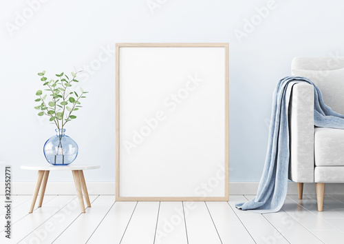 Poster mockup with vertical wooden frame standing on floor in living room interior with sofa and branches in blue vase on empty wall background. 3D rendering, illustration.