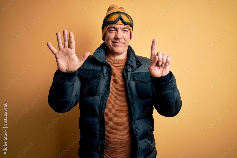 Middle age handsome grey-haired skier man on vacation wearing ski goggles showing and pointing up with fingers number six while smiling confident and happy. Middle age handsome grey-haired skier man on vacation wearing ski goggles showing and pointing up with fingers number six while smiling confident and happy.