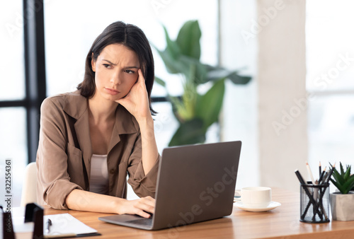 European young manager looking away using computer