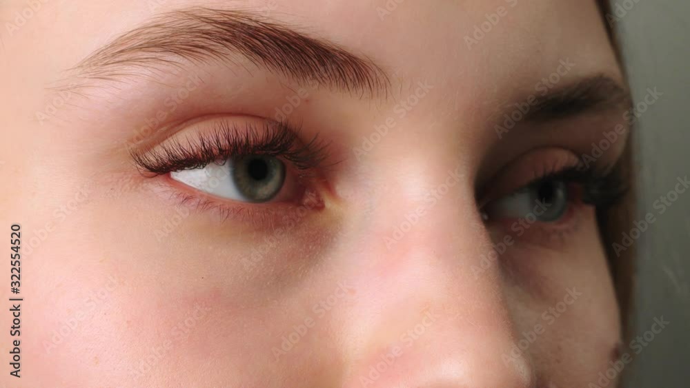 Eyelash Extension Procedure. Woman Eye with Long Blue Eyelashes. Ombre effect. Close up, selective focus.