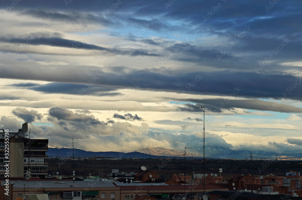  A view of the mountains, with a cloudy sky and an antenna and rooftops